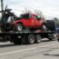 A Large Blue Tow Truck With A Smaller Red Tow Truck In Its Truck Bed, On The Way For Repair