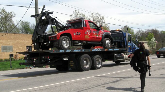 A Large Blue Tow Truck With A Smaller Red Tow Truck In Its Truck Bed, On The Way For Repair
